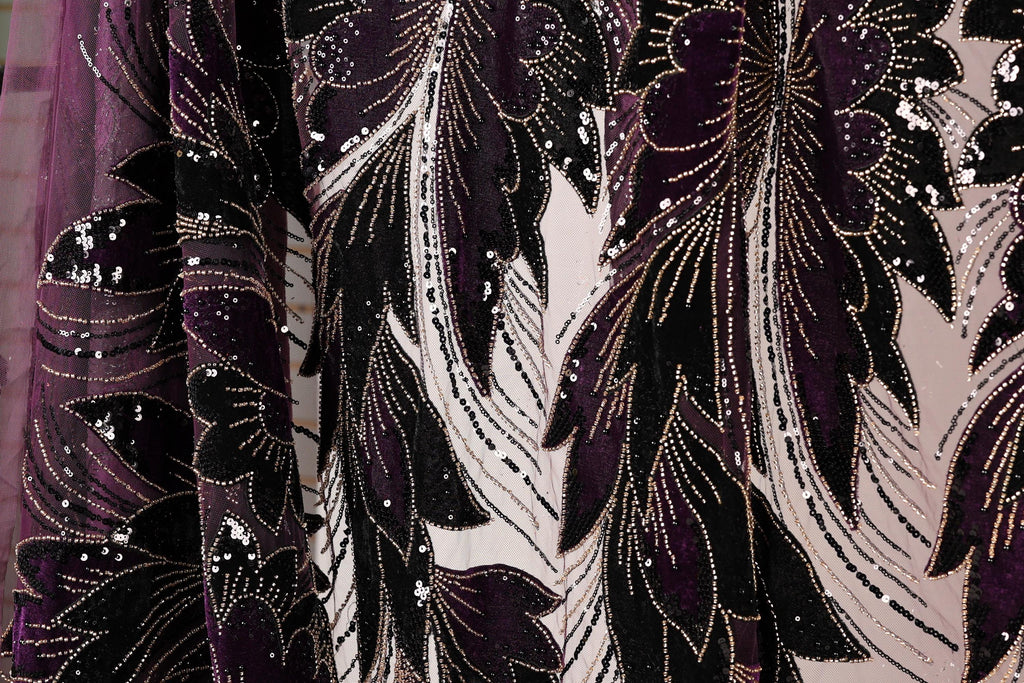 a close-up view of a fabric with a floral pattern in shades of purple and black, adorned with sequins.