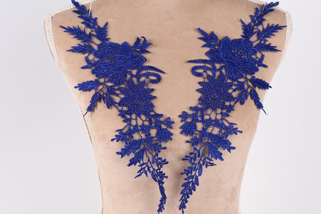 a mannequin torso with two blue floral embroidered patches on it.