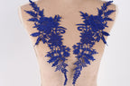 a mannequin torso with two blue floral embroidered patches on it.