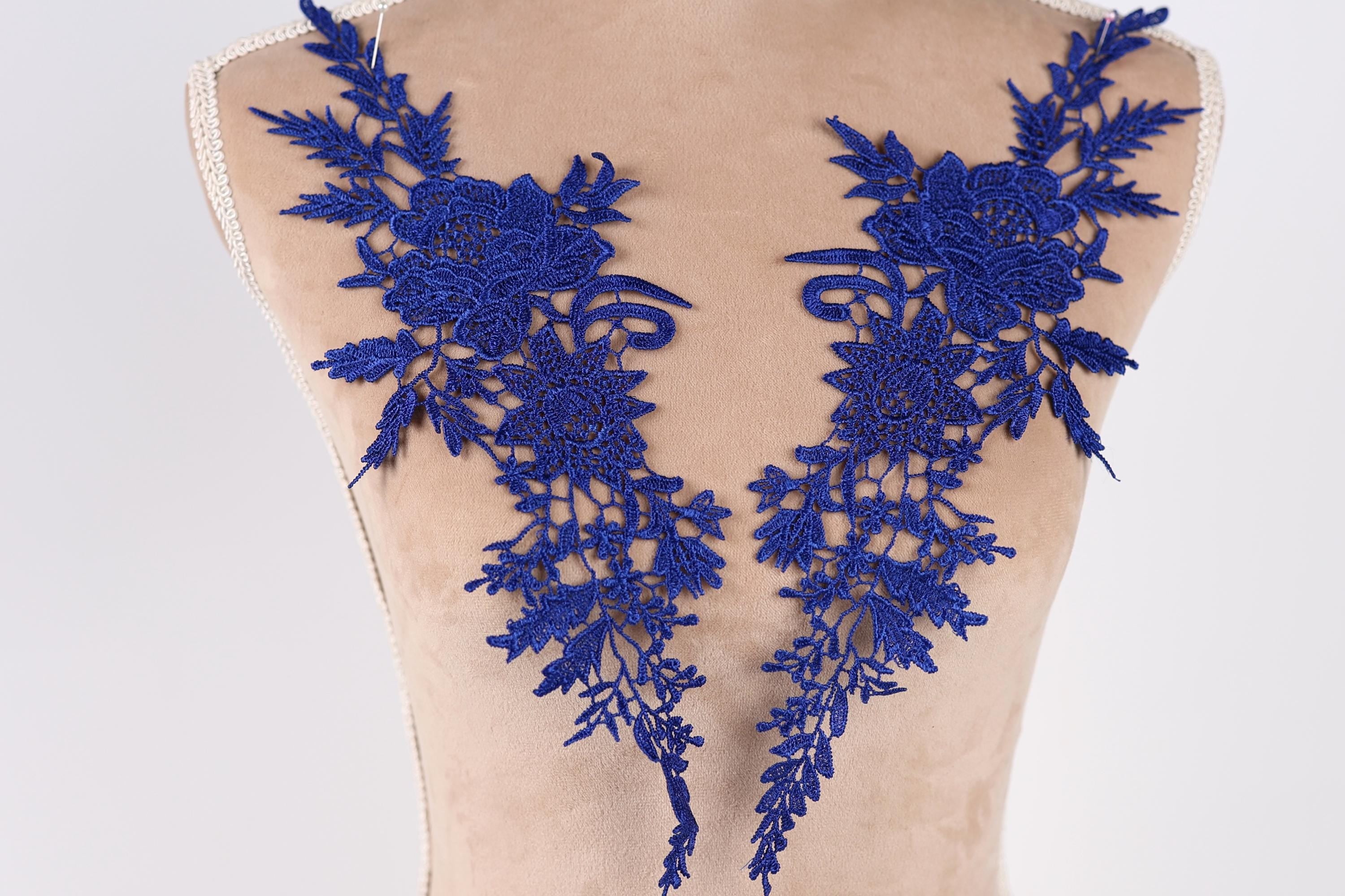 a mannequin torso with two blue floral embroidered patches on it.