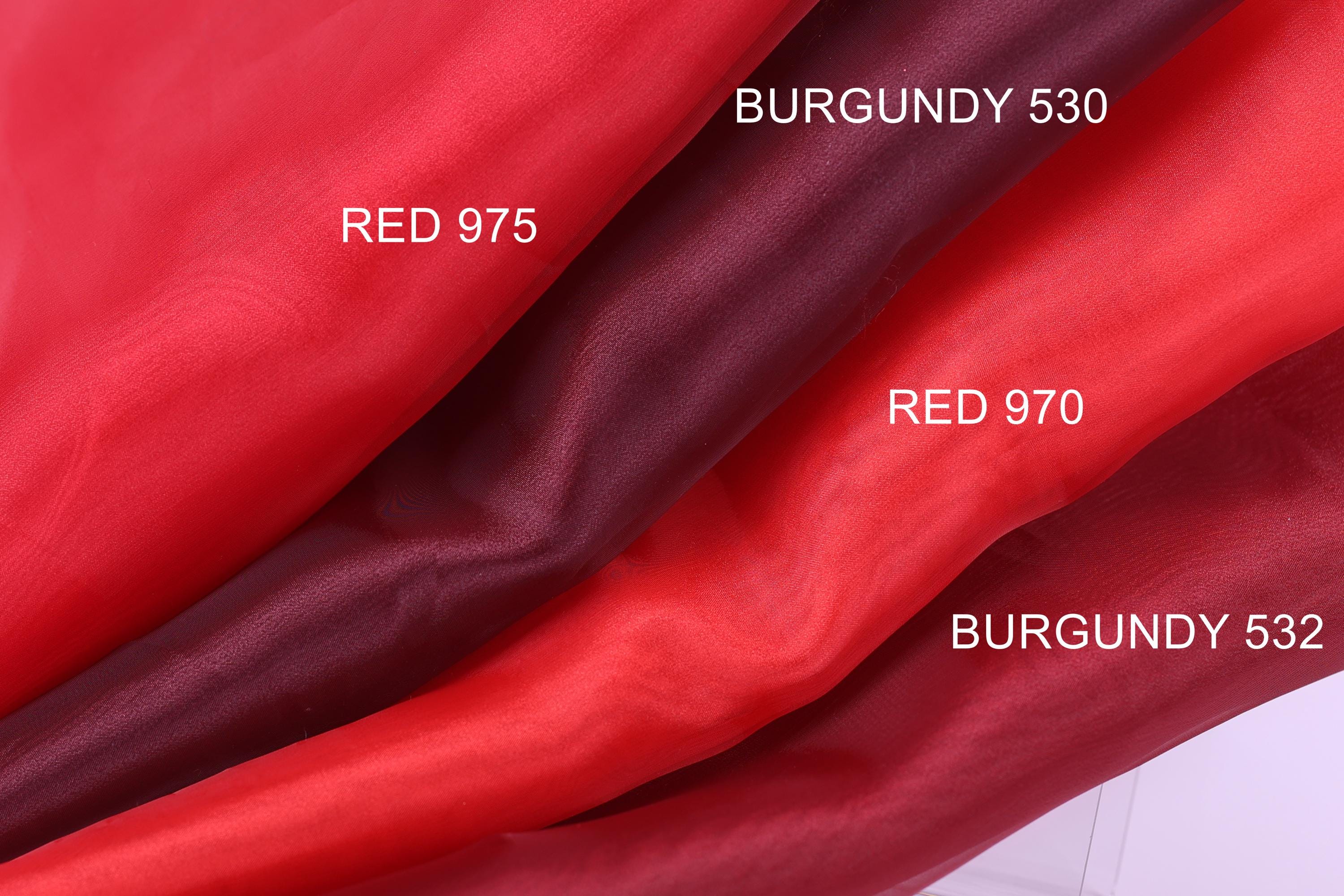three different shades of red fabric, with each shade labeled with the name of the fabric.