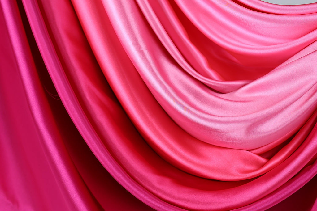 The image is a close-up of a fabric with a gradient of pink and red colors, creating a visually striking and vibrant appearance.
