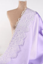 A mannequin wearing a lavender satin fabric with a delicate white lace trim.