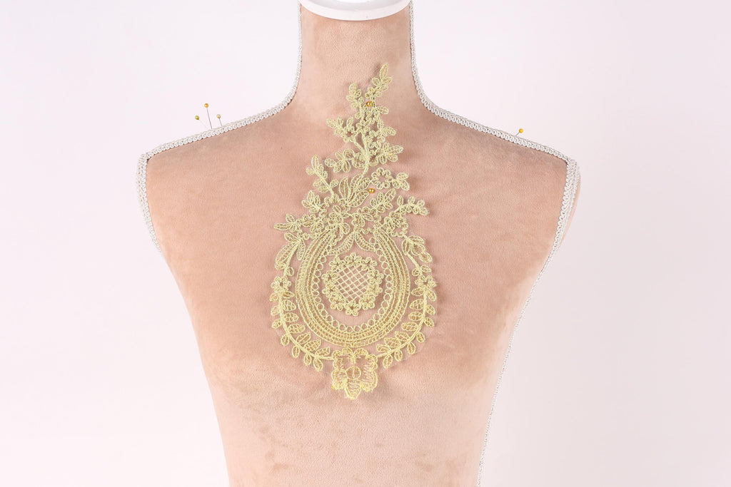 A mannequin with a decorative gold lace piece on its back.
