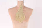 A mannequin with a decorative gold lace piece on its back.
