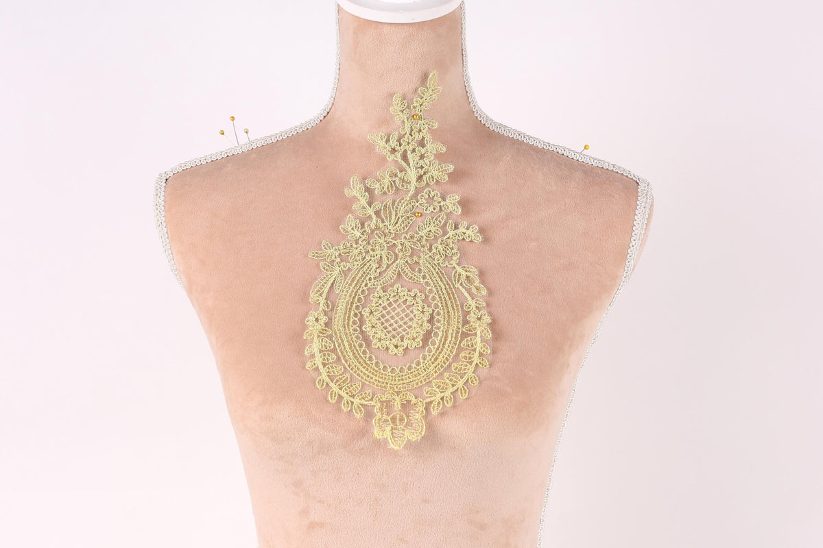 A mannequin with a decorative gold lace piece on its back.