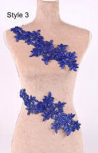 A mannequin wearing a dress with a decorative blue floral lace overlay.