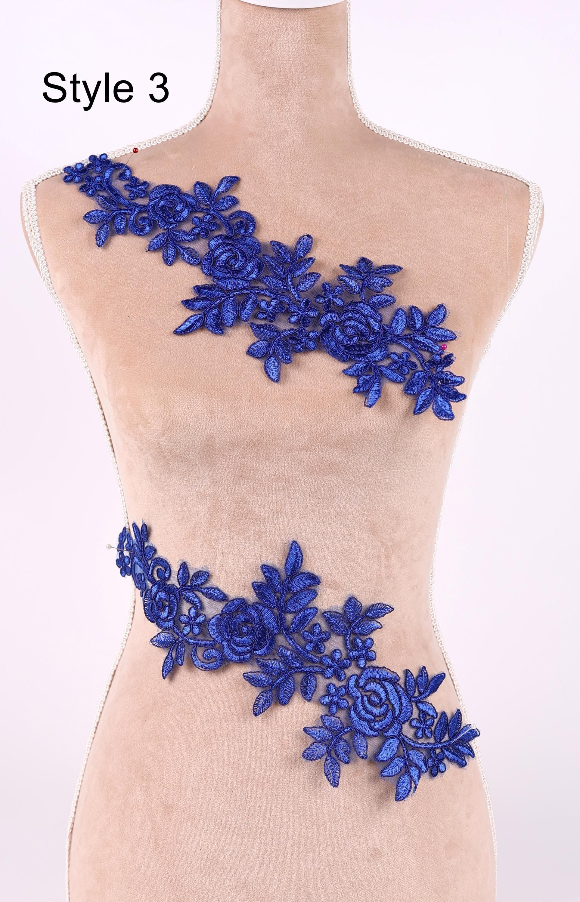 A mannequin wearing a dress with a decorative blue floral lace overlay.