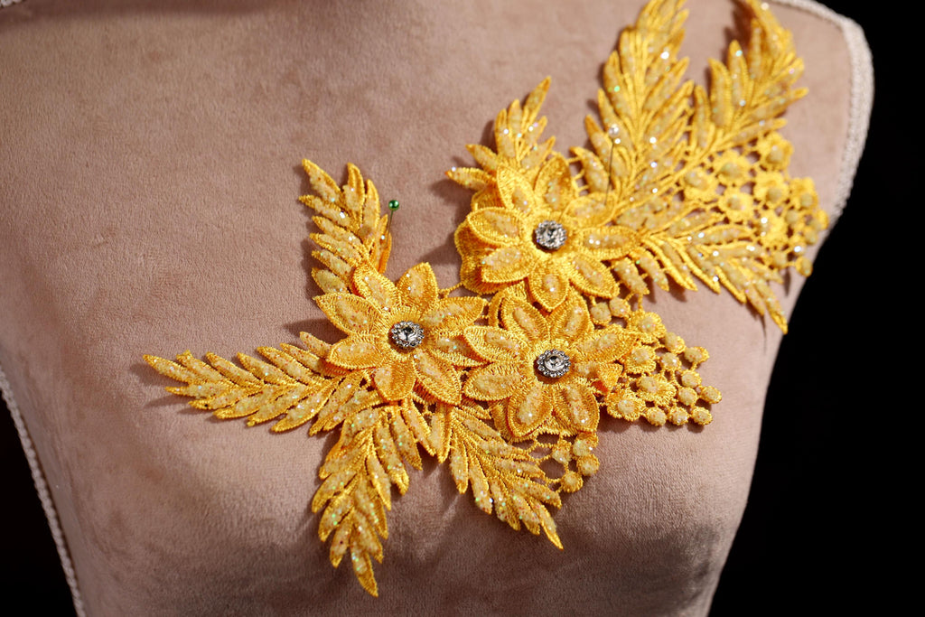 A close-up of a mannequin torso with a decorative gold embroidered flower on the left side.