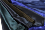A close-up view of various colored satin fabric, including shades of blue, green, and brown, arranged in a pile.