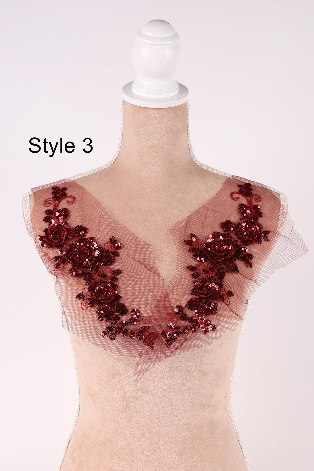 A mannequin wearing a red floral-embellished dress with a white headband.