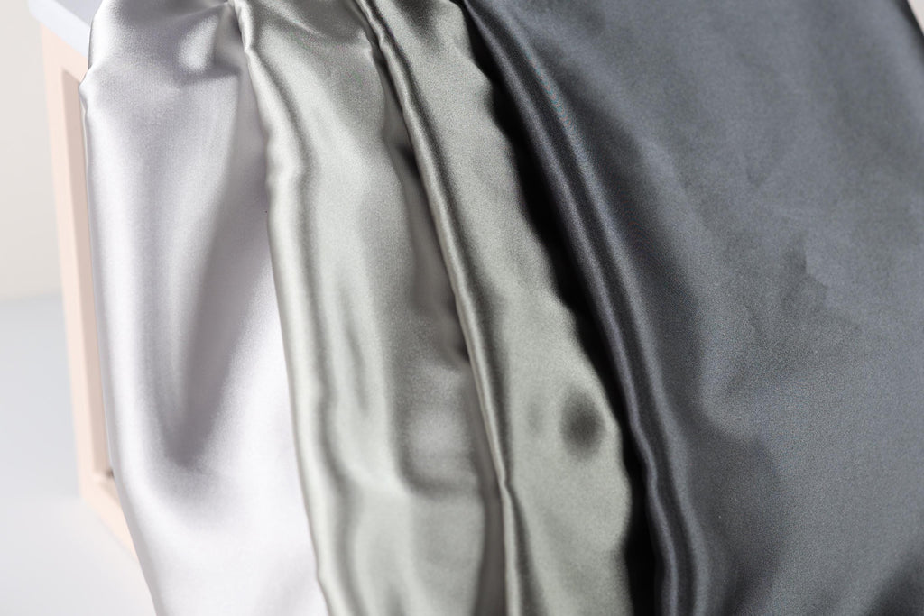 a close-up view of three different colored satin fabrics, with a focus on the color variations and texture of the fabric.