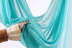 A hand is holding a piece of blue fabric, which appears to be a sheer or sheer curtain.