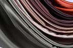 A close-up view of a collection of colorful satin fabric, with a gradient of colors ranging from dark to light brown.