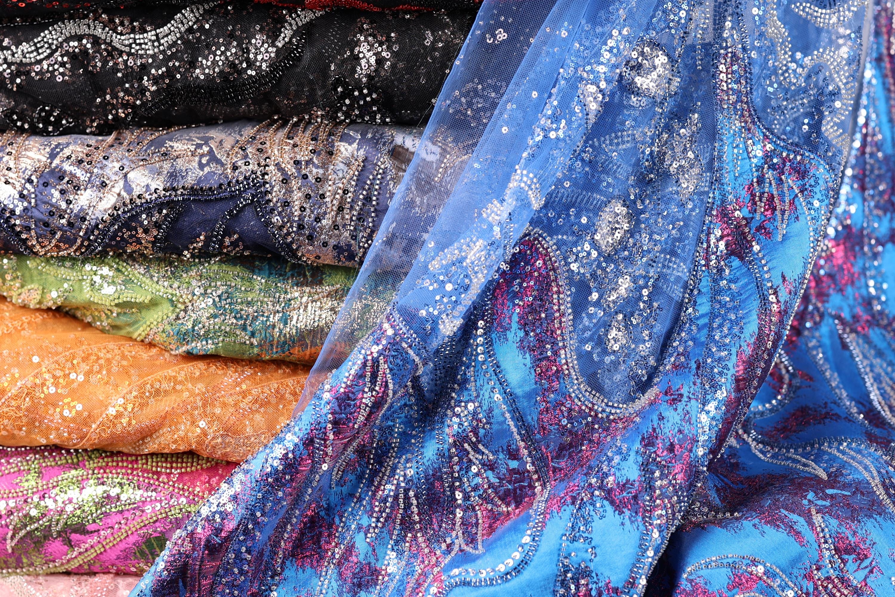 A close-up view of a stack of colorful, patterned fabric pieces, with a focus on the intricate designs and textures of the materials.