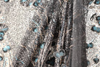 The image is a close-up of a fabric with a black and white pattern, featuring a mix of blue and black elements. The fabric appears to be made of sequin material, with a floral pattern visible on the left side.