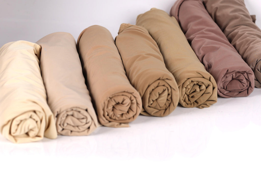 A row of rolled-up fabric pieces in various shades of brown, including light brown, dark brown, and a darker shade of brown.