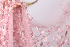 A close-up view of a delicate pink fabric with a floral pattern, featuring a lace-like texture and sequin accents.