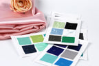 a collection of fabric swatches, each with a different color, laid out on a white background. A single pink rose is also present in the scene.