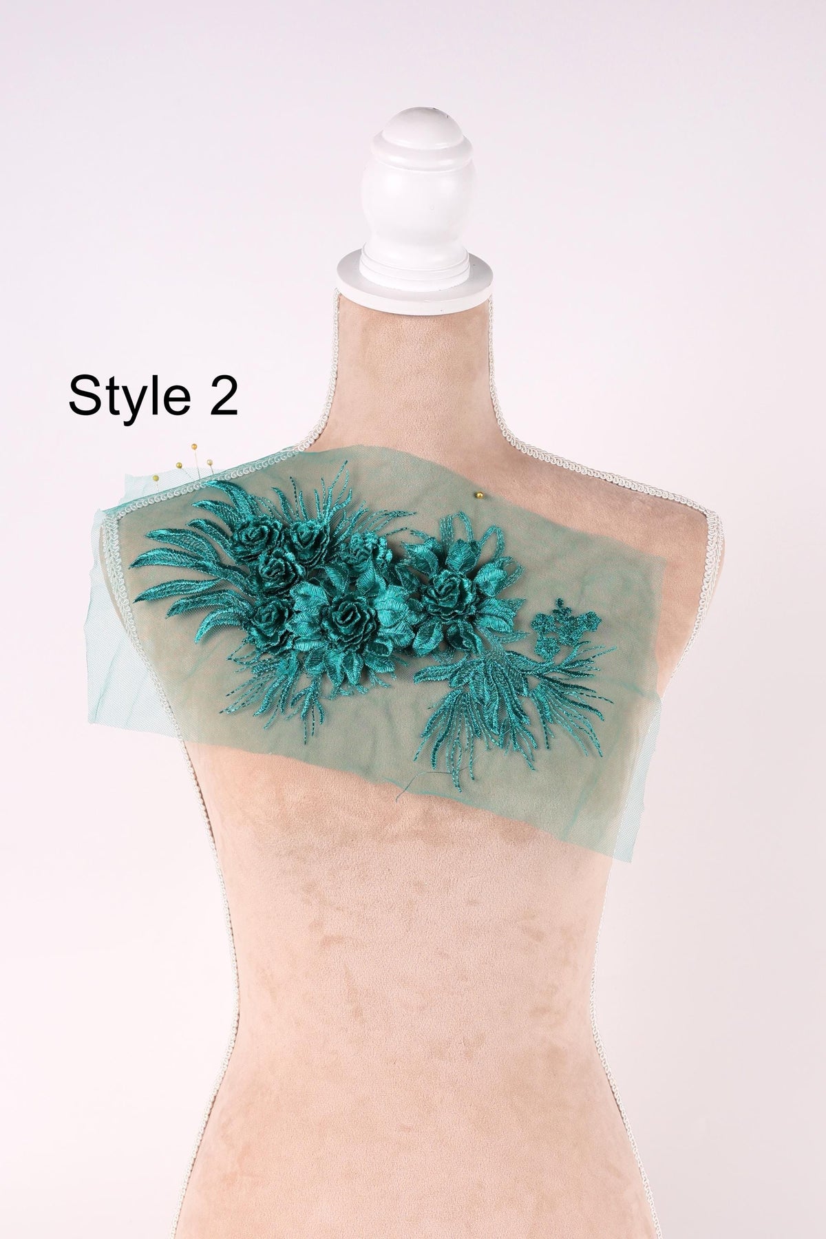 A mannequin with a floral embroidered patch on its shoulder, featuring a combination of green and blue flowers.