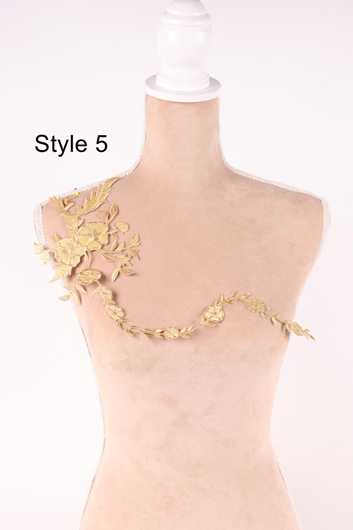 A mannequin with a gold embroidered design on its shoulder, featuring a floral pattern.