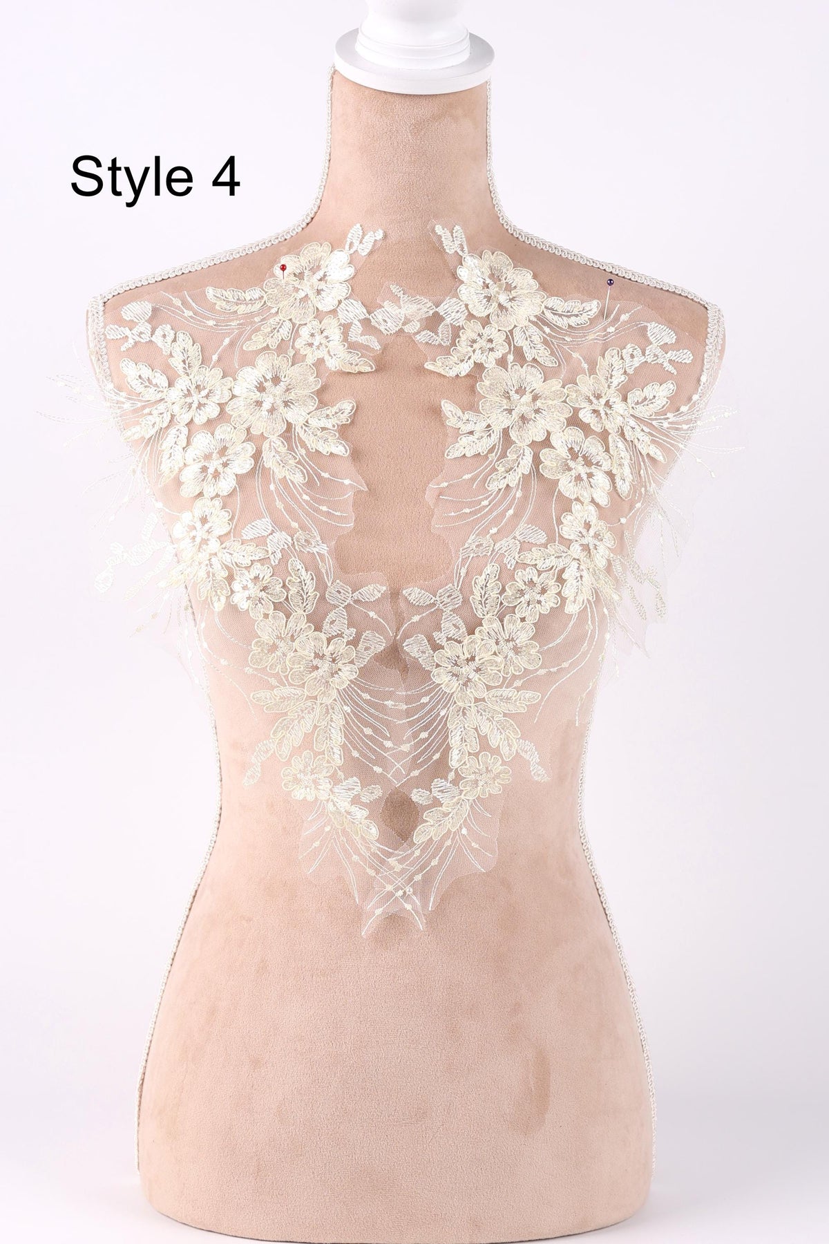 A mannequin wearing a white lace dress with intricate floral patterns on the bodice.