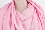 A close-up view of a pink fabric draped over a person's neck, with a necklace visible.