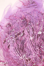 The image is a close-up view of a fabric with a pink and purple floral pattern, featuring sequins and beads that create a visually striking and intricate design.
