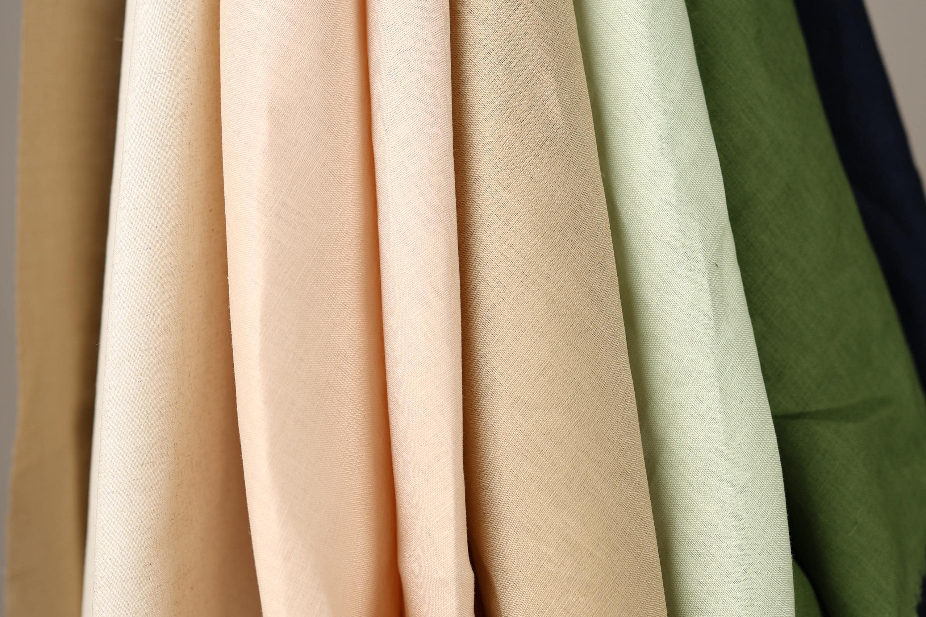 A close-up view of various fabric swatches in different colors, including peach, beige, and green.