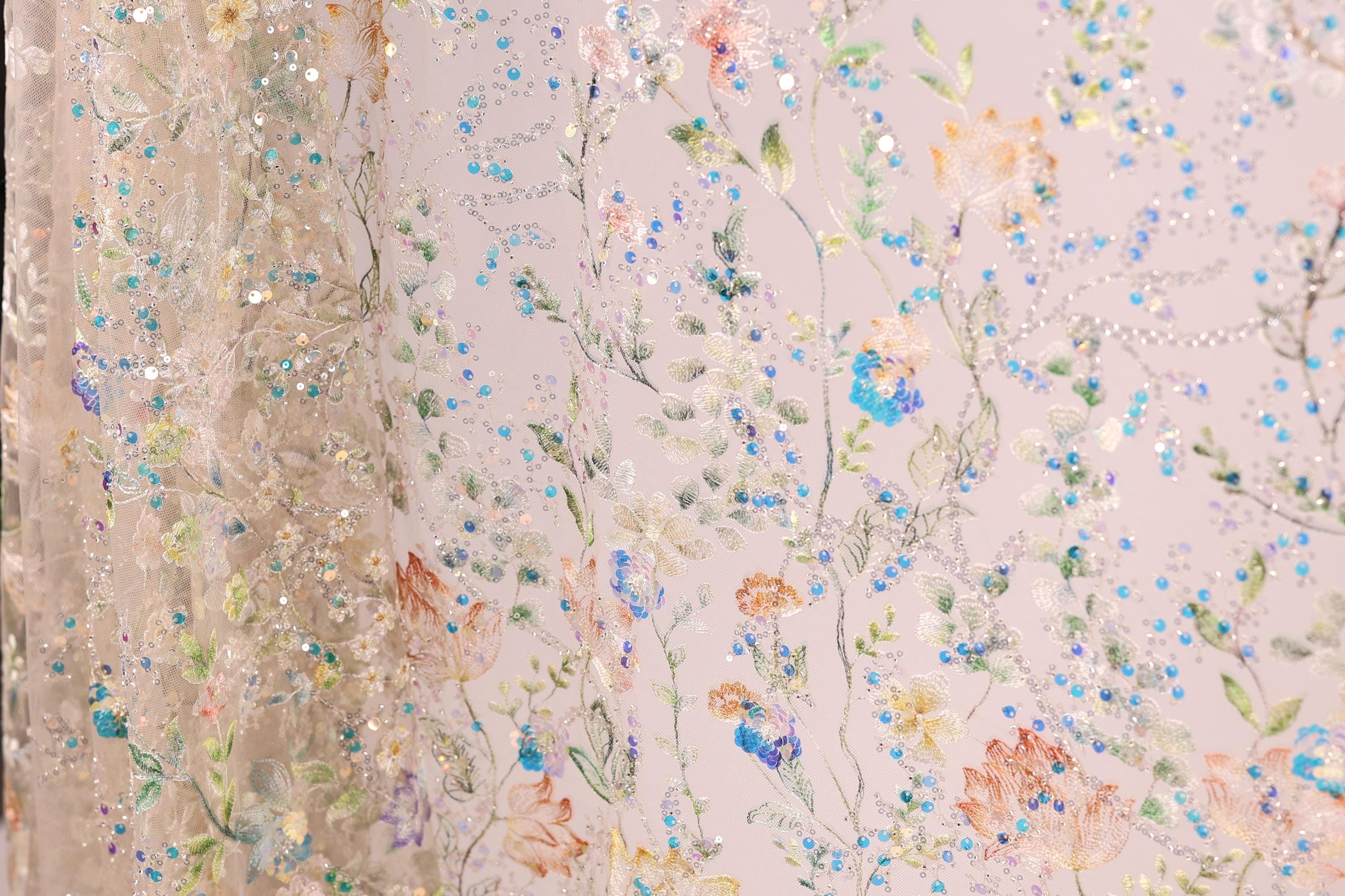 The image is a close-up of a fabric with a floral pattern, featuring various colors and designs of flowers and leaves.