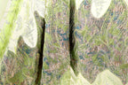 a close-up view of a fabric with a vibrant, multicolored pattern. The fabric appears to be a blend of green, blue, and pink hues, creating a visually striking and intricate design. The fabric is folded and crumpled, adding texture and depth to the image.