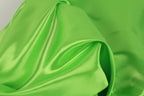 A close-up view of a bright green fabric, possibly silk or satin, with a smooth and shiny texture.