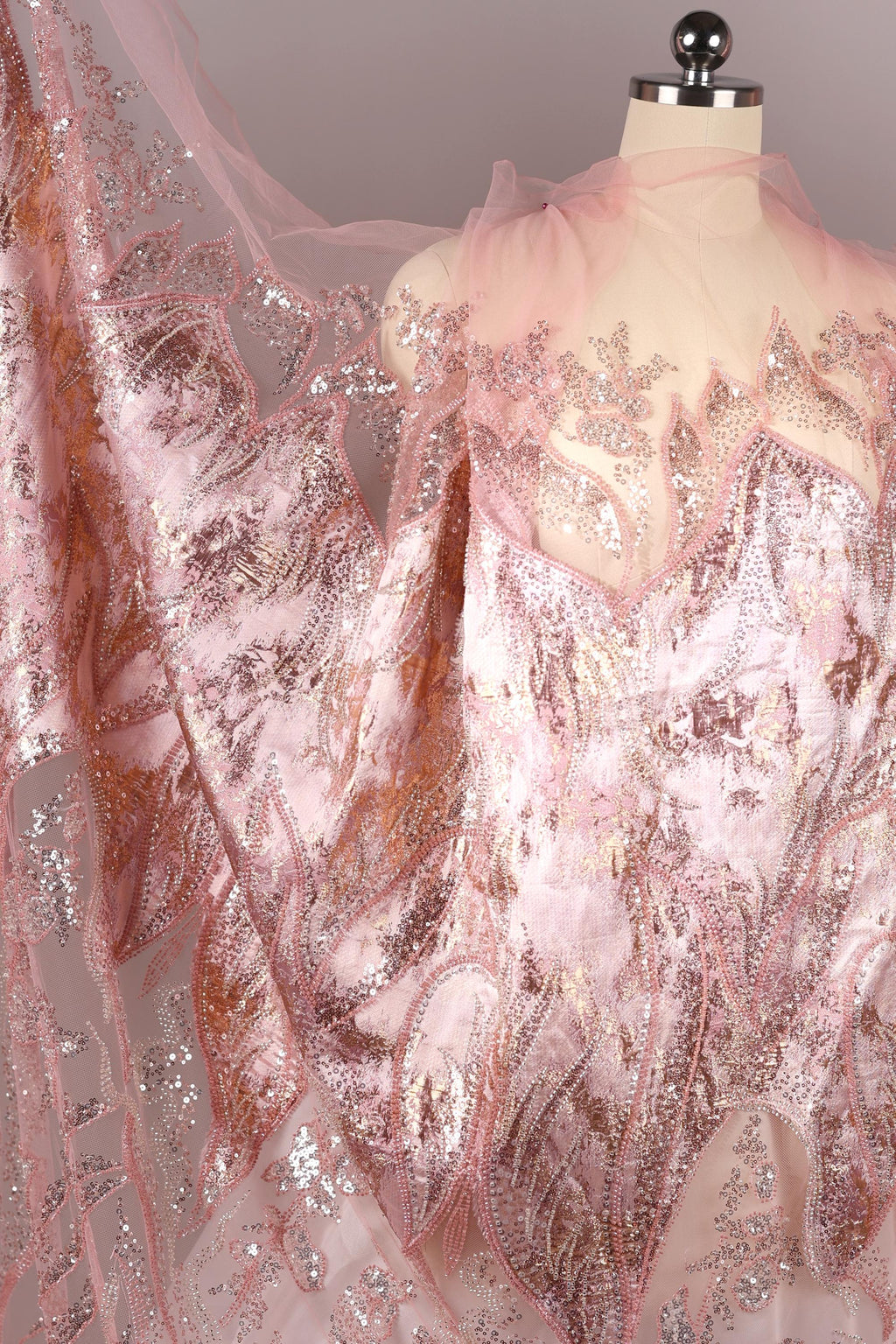 a mannequin wearing a pink and gold sequined dress with a sheer, flowing skirt.