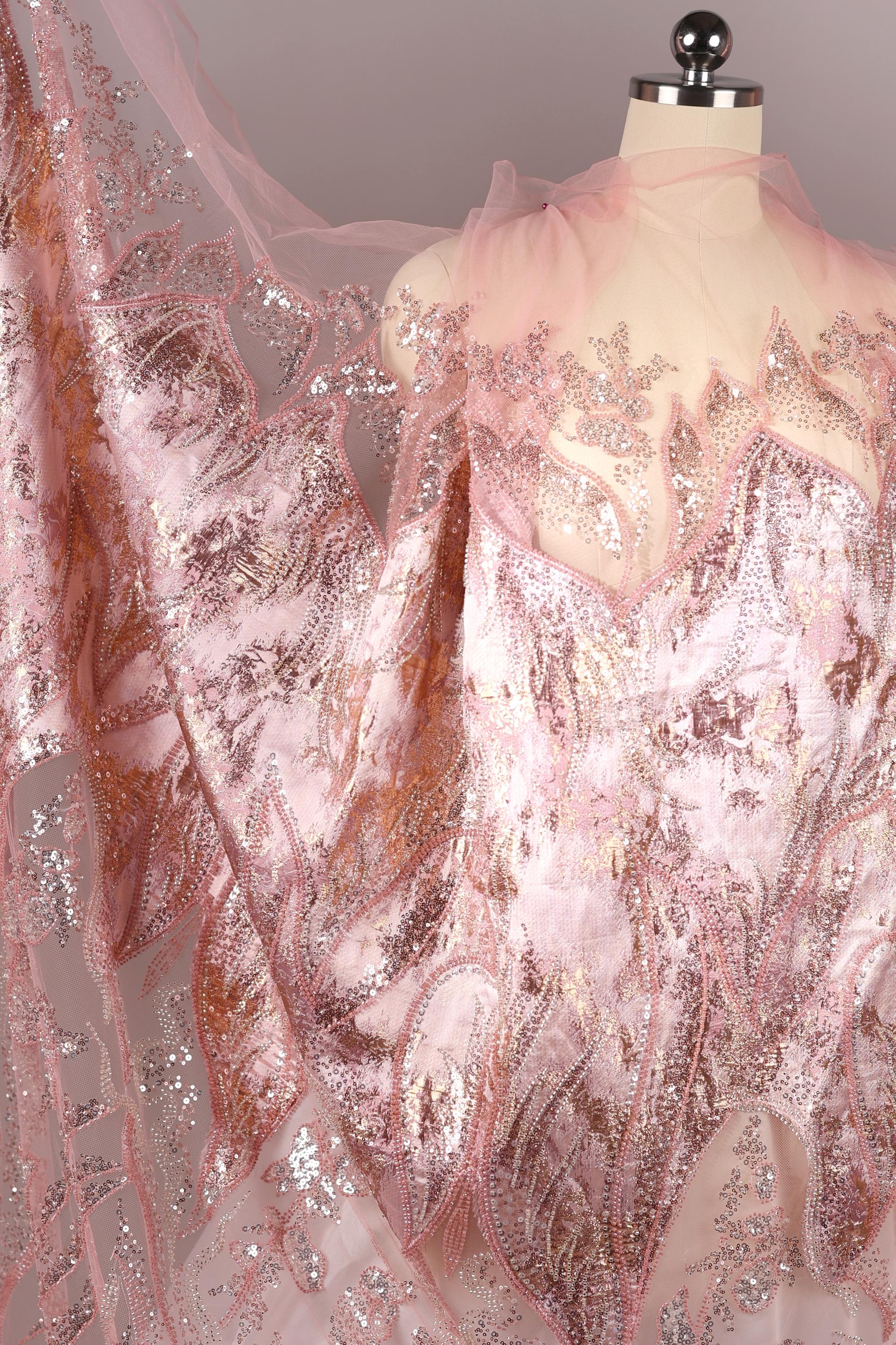 a mannequin wearing a pink and gold sequined dress with a sheer, flowing skirt.