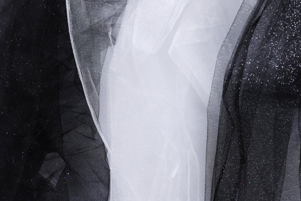 a close-up view of three different fabric textures, including black, white, and glittery black fabric.