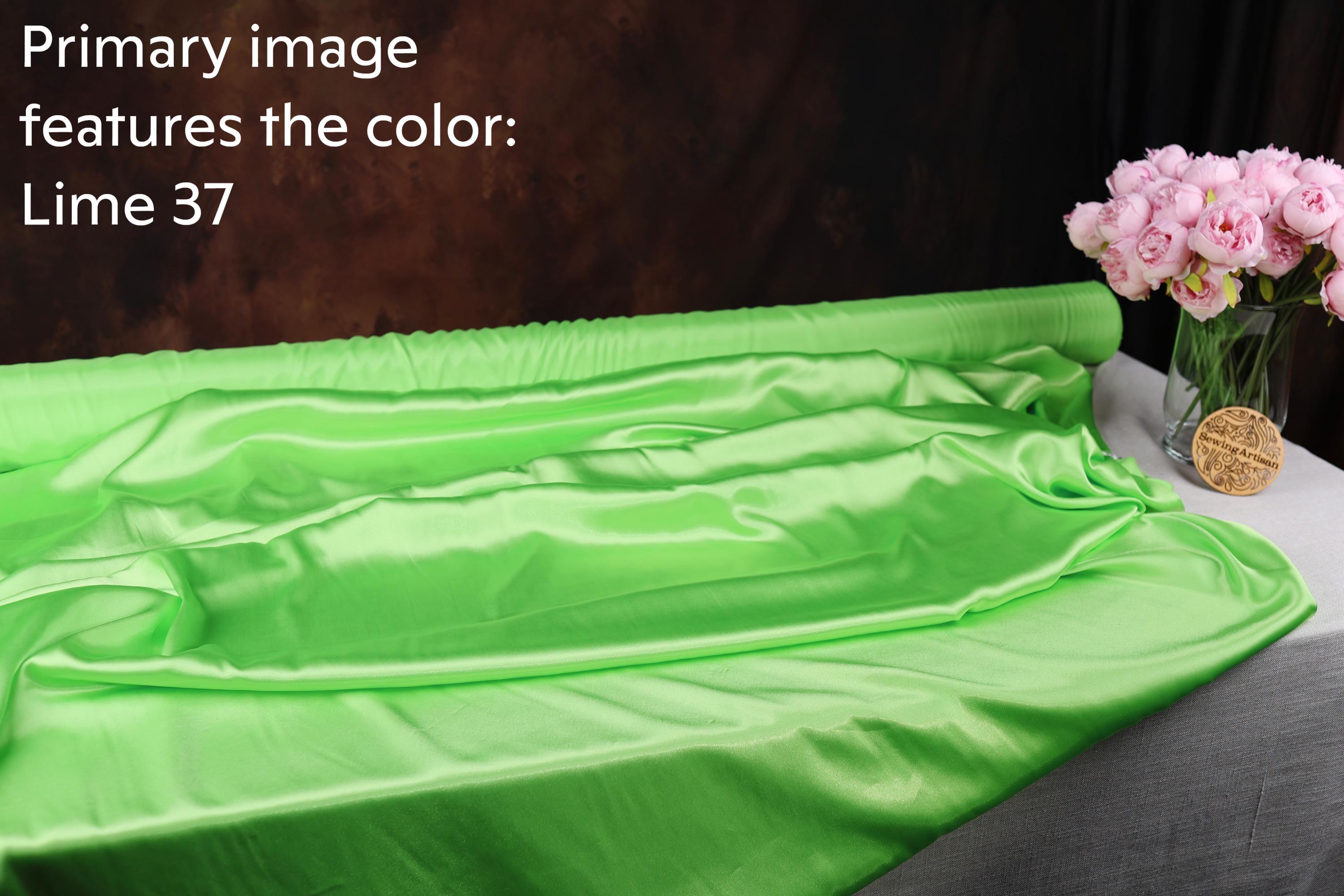 a green satin fabric with a floral arrangement of pink flowers placed next to it.