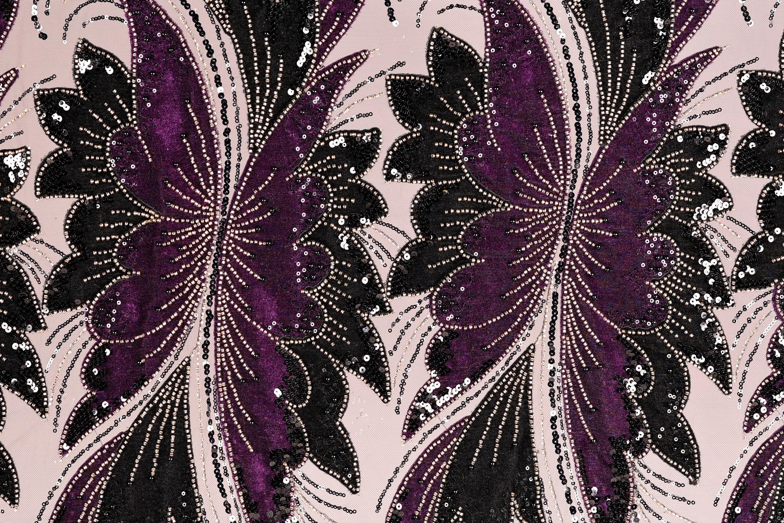 a close-up view of a fabric with a repeating pattern of purple and black butterfly-like shapes, adorned with sequins and beads.