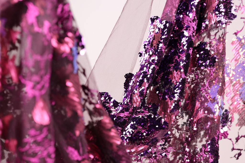 a close-up view of a fabric with a vibrant mix of purple and pink sequins, creating a visually striking and eye-catching pattern.