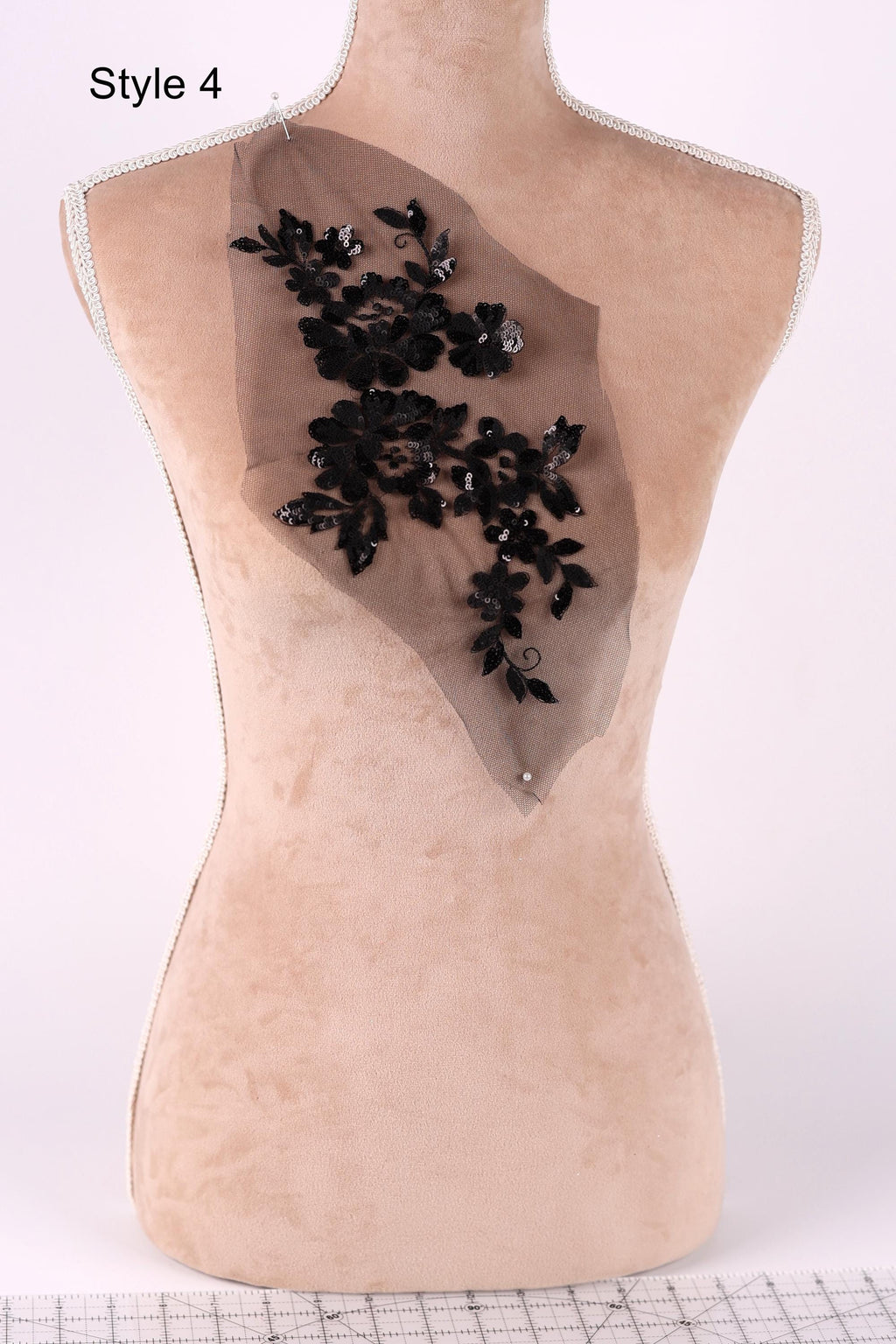 A mannequin with a beige body and a black floral embroidered on the back.