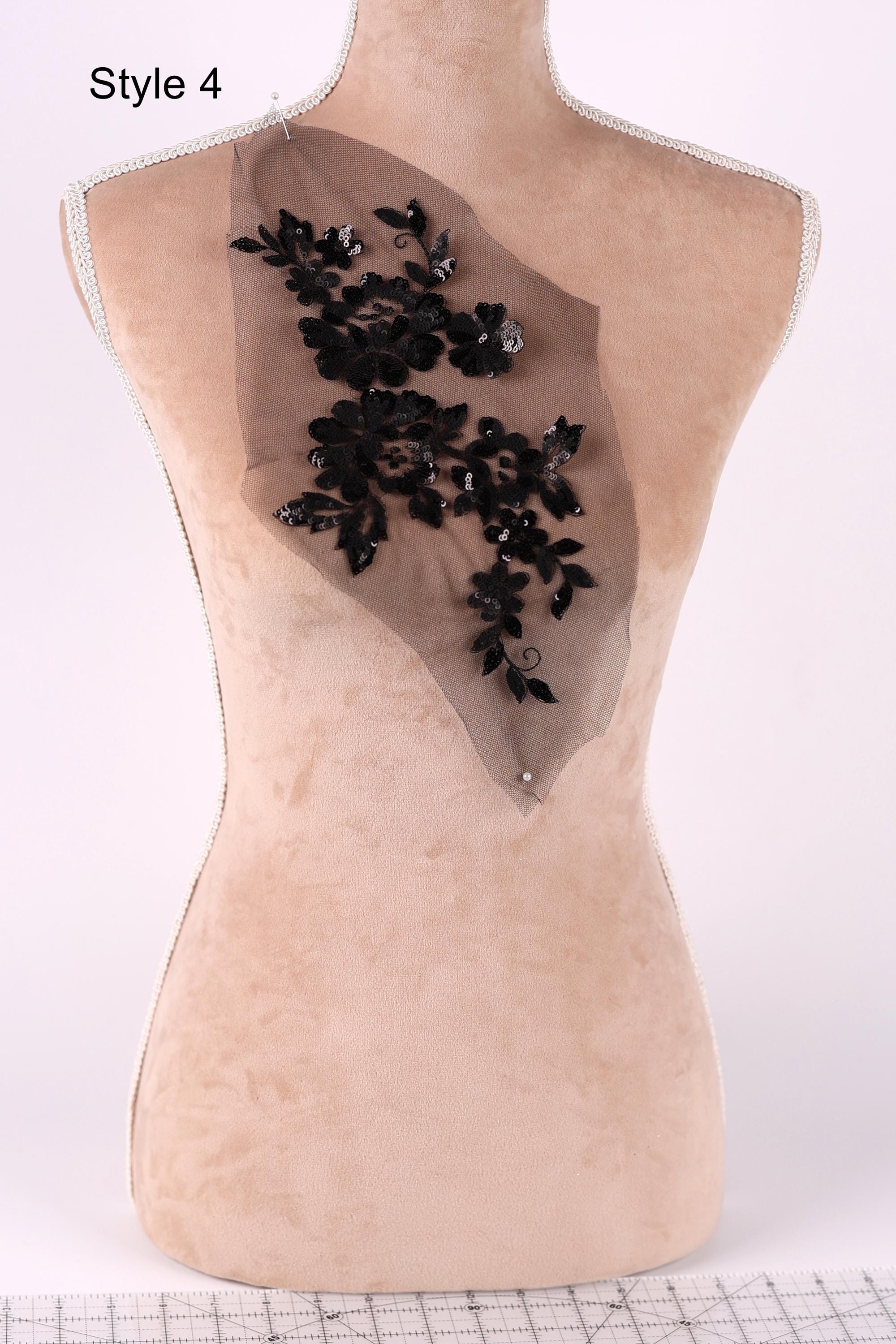 A mannequin with a beige body and a black floral embroidered on the back.