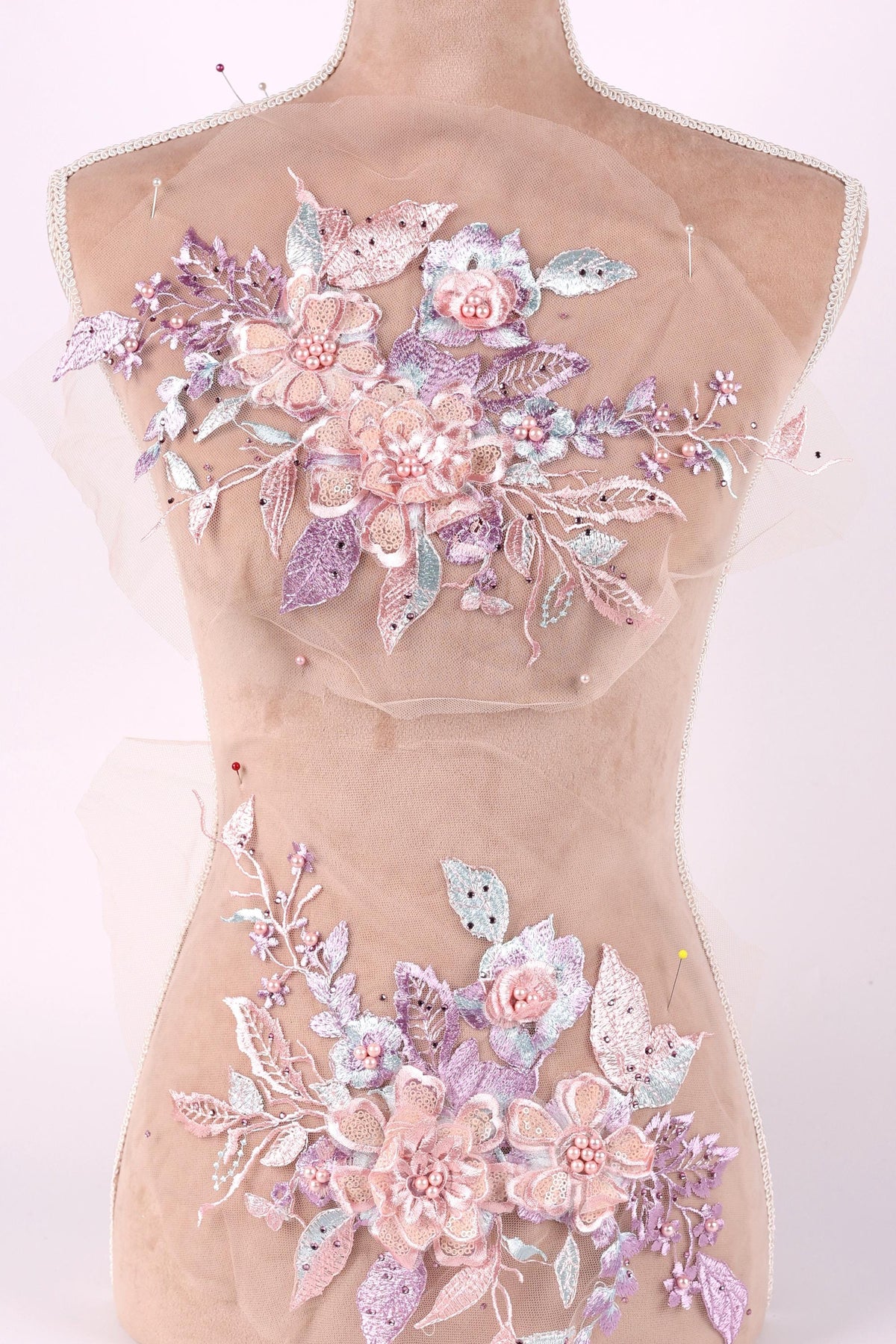 A mannequin torso with a decorative floral design on it, featuring a variety of pink and purple flowers and leaves.
