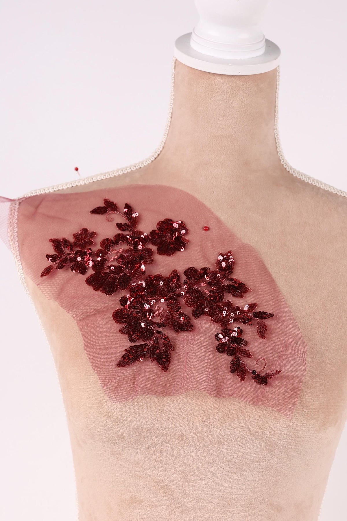 a close-up view of a person's arm with a pink fabric adorned with red sequins.