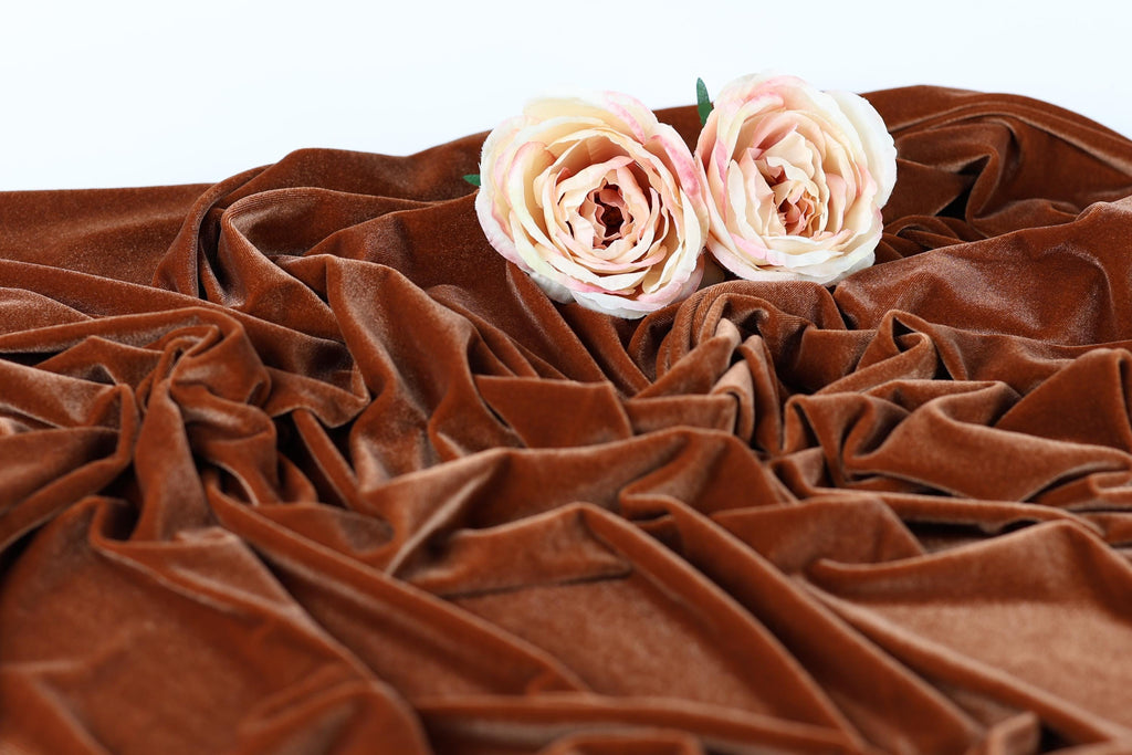 Two pink roses resting on a crumpled brown fabric.
