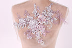 a delicate and intricate floral embroidery design on a mannequin or dress form, showcasing a variety of pink and white flowers and leaves.