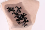 a close-up view of a mannequin torso with a decorative black floral embroidered on it.