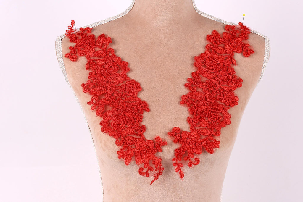 A mannequin torso with red floral lace pieces sewn onto it.