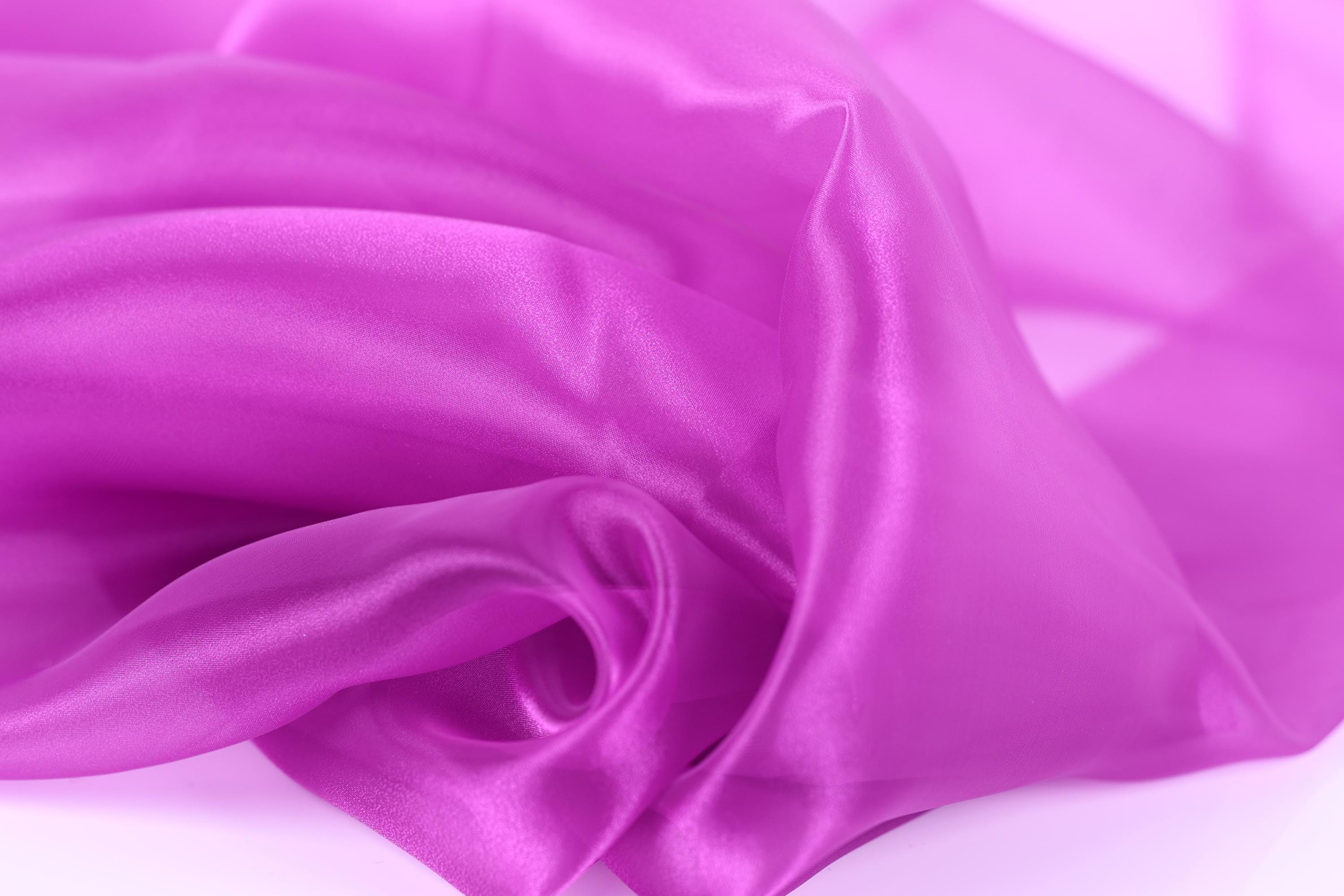 The image is a close-up of a soft, shiny, and smooth fabric in a vibrant shade of purple.