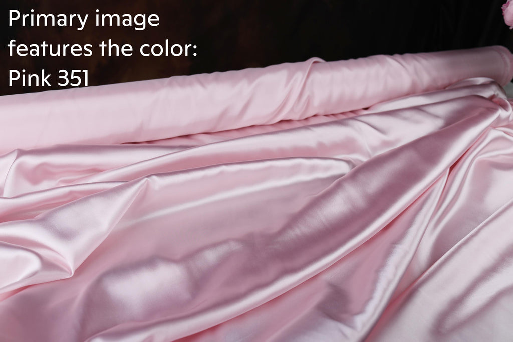 a close-up view of a soft, shiny pink satin fabric, possibly silk or satin, with a dark background.