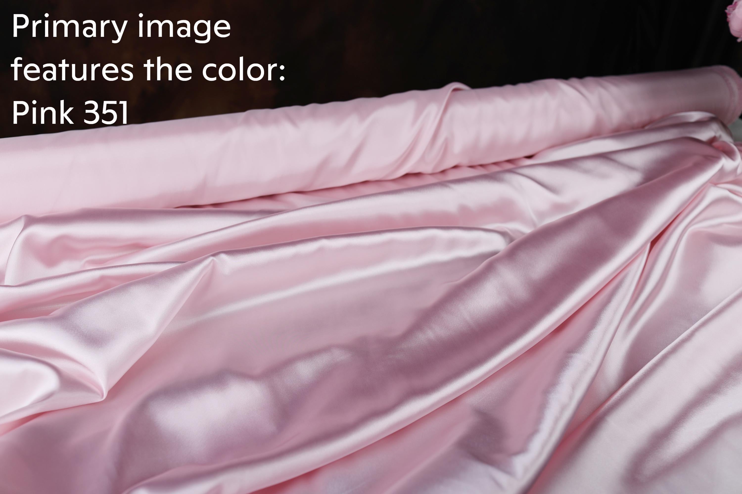 a close-up view of a soft, shiny pink satin fabric, possibly silk or satin, with a dark background.