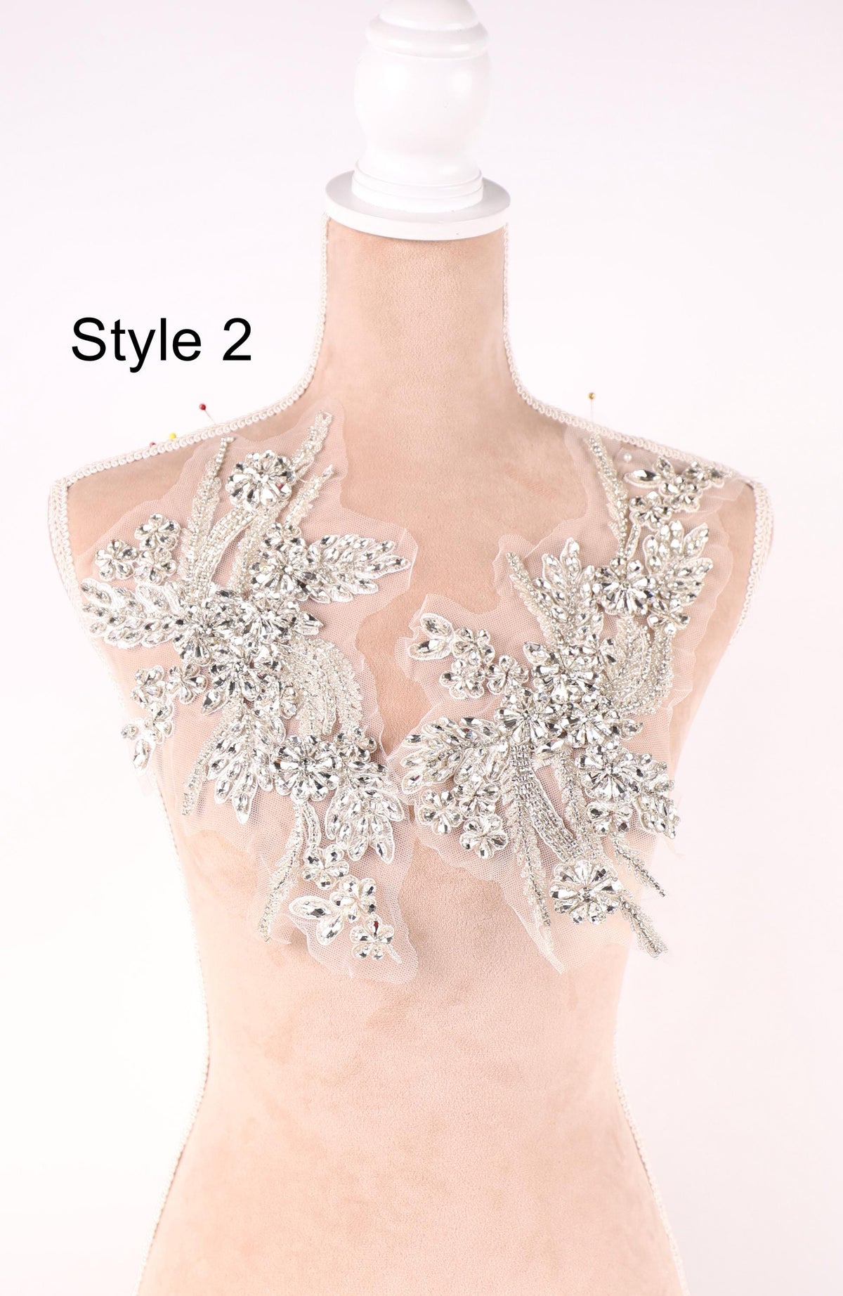 A mannequin wearing a dress with a large, intricate, and sparkling embellishment on the neckline.